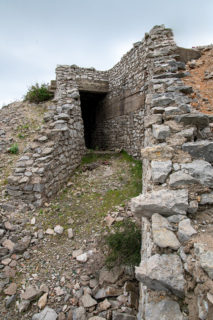 Mur de gorge en pierre de l'abri souterrain du projecteur/groupe électrogène, avec porte et couloir d'accès
